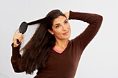 Woman in brown v-neck sweater brushing her hair
