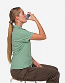Woman with long hair sitting on stool and using inhaler