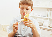Sitting boy peeling a banana