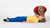 Girl lying on back being resuscitated by woman
