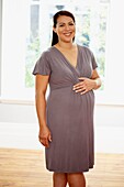 Pregnant woman in short sleeved dress, smiling