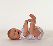 Smiling baby girl lying on back with legs and arms up