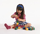Girl sat on floor playing with building bricks