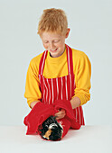 Young boy holding a long haired guinea pig with a towel