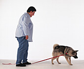 Woman standing on a leash with dog walking ahead