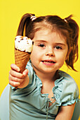 Girl sitting on a blue seat eating an ice cream cone