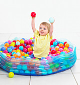 Boy amongst balls held in a large plastic swimming pool