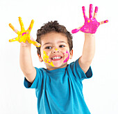 Boy with yellow and pink paint on his hands and face