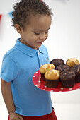 Boy looking at plate of muffins