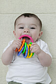 Baby boy biting plastic ring toy