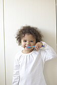 Girl bushing teeth with blue toothbrush