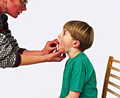 Pressing on boy's mouth wound with pad