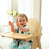 Baby girl sitting in high chair clapping