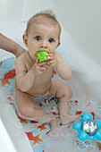 Baby girl in bath with toys