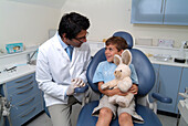 Dentist sat next to boy in dentist's chair