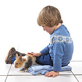 Boy sitting with rabbit on blanket
