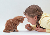 Girl in a yellow top playing with ginger kitten