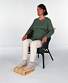 Seated pregnant woman with feet on rolled towel