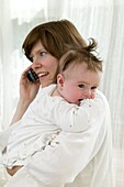 Woman on mobile phone holding baby girl