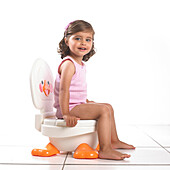 Girl wearing vest sitting on white potty