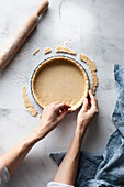 A baker pressing pastry into a pan