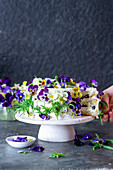Vanilla buttercream cake with blueberries, decorated with pansies