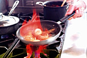 Mushroom caps being flambéed with cognac in a commercial kitchen setting