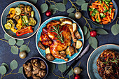 Christmas evening celebrating table with baked chicken, roasted ham, vegetables, decorated with eucalyptus branches