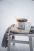 Verschütteter schwarzer Kaffee mit Holztablett auf Hocker im Schnee