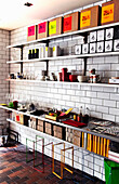 Modern shelves with crates, boxes and crockery on a white tiled wall