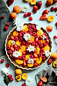 Fruit tart with apricots and raspberries decorated with flowers