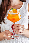 Woman holding glass with sea buckthorn spritz