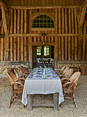 Long, set table with rattan chairs in front of French country house