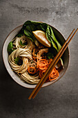 Asian noodle bowl with bok choy, spiralled carrots, fresh mint and lemon
