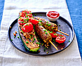 Minced meat skewers and fried zucchini with tomatoes