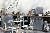 Delicate table and chairs in front of outdoor kitchen made of galvanised steel