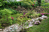 Sommerlicher Garten mit Natursteinen und Trockensteinmauer