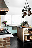 Kitchen with an island with a hanging cast iron pot rack and concrete countertops
