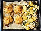 Crispy chicken legs with zucchini and potato vegetables on a baking tray