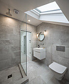 Simple bathroom with shower, concrete tiles and skylight