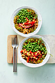 Vegan spicy rice bowl with peas, peppers and peanuts