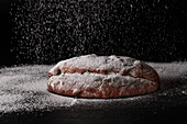Stollen being dusted with icing sugar