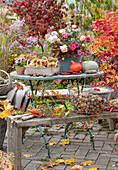 Autumn terrace: autumn bouquet with roses, rose hips and autumn asters, baskets with walnuts and chestnuts, pumpkins, chillies, rose hips and pansies.