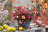 Herbstlicher Strauß aus Rosen, Hagebutten, Herbstastern und Chrysanthemen, Quitten als Dekoration
