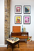 70s radio and stool below framed posters on wall