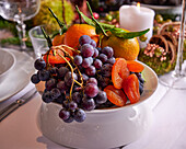 A fruit bowl with grapes, dried apricots and mandarins