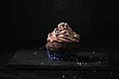 A vegan chocolate muffin with chocolate nougat frosting and sugar pearls