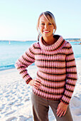 A blonde woman wearing a striped jumper on the beach