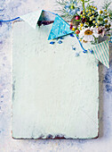 A white glazed wooden board, flowers and bunting