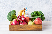 Fruit, greens, vegetables and fresh smoothie in wooden tray